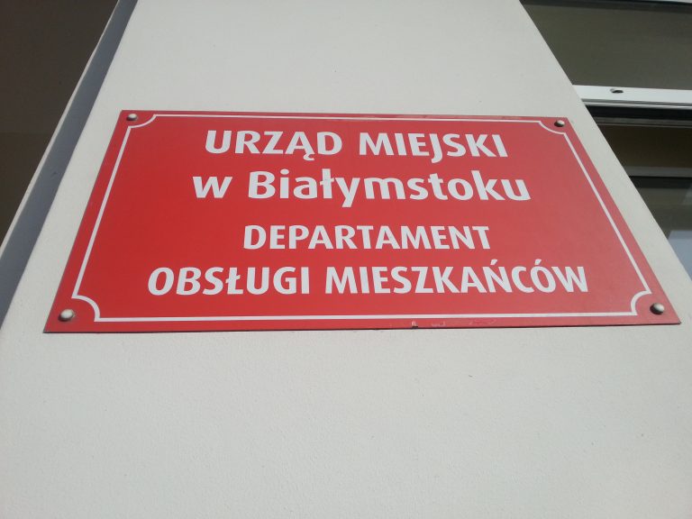 Czerwona tabliczka na ścianie budynku urzędu