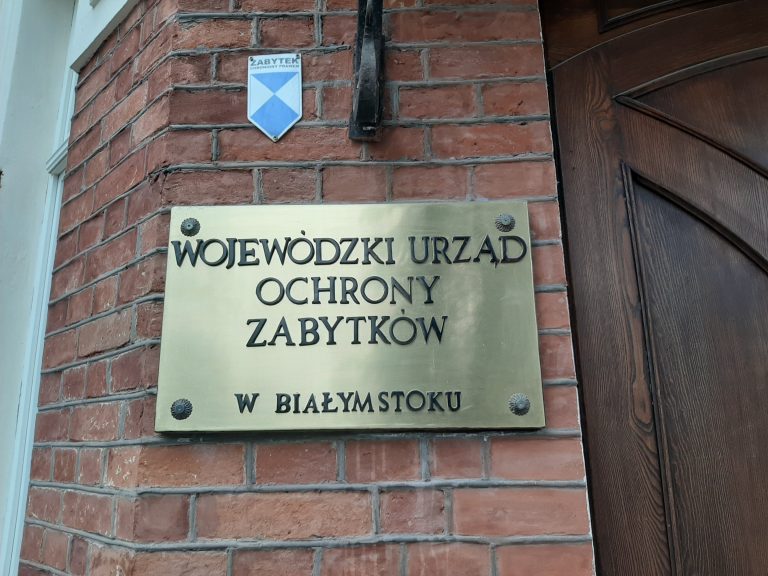 Ceglana ściana a na niej złota tabliczka z napisem Wojewódzki Urząd Ochrony Zabytków