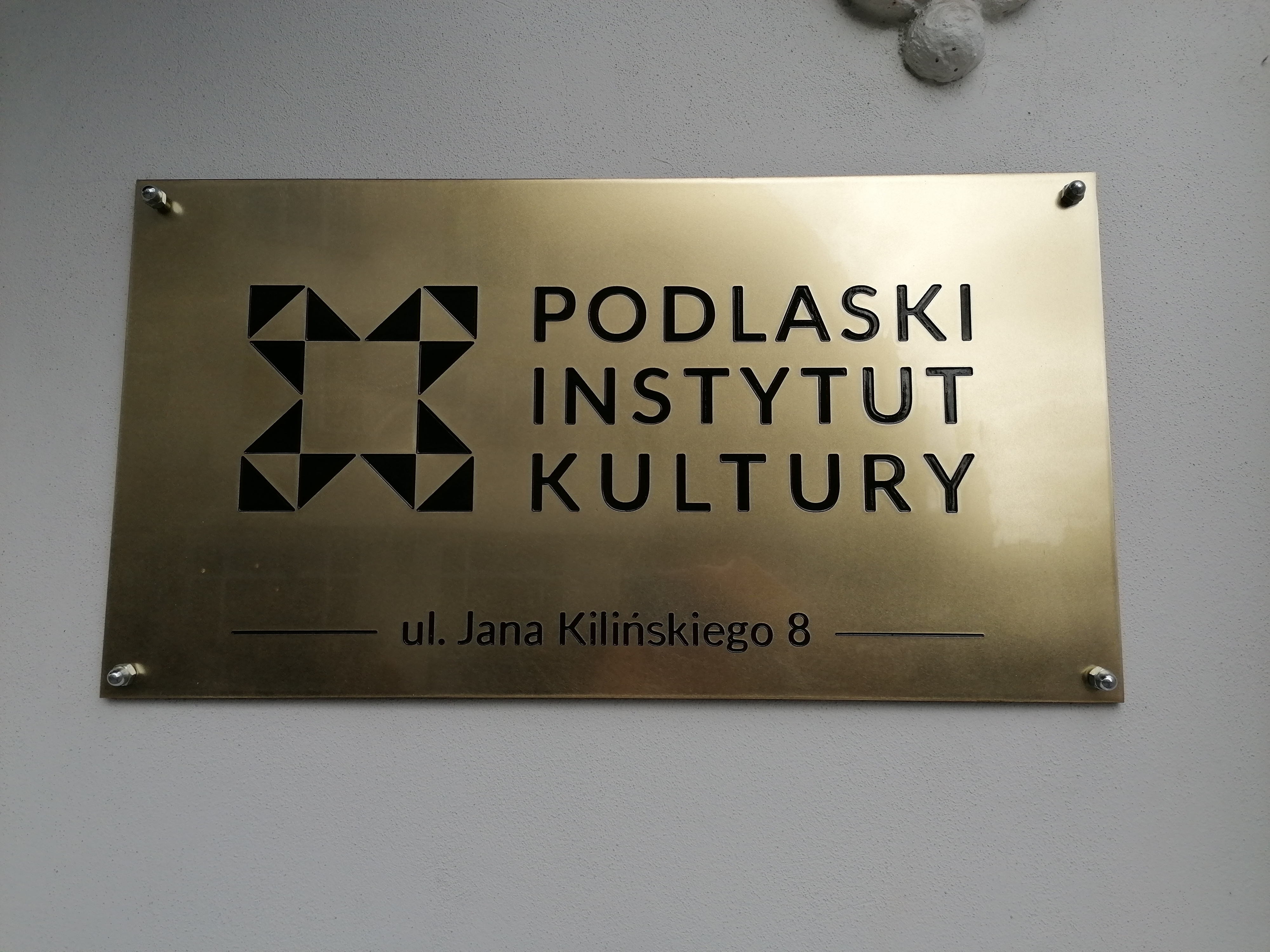 Złota tabliczka ścienna z napisem Podlaski Instytut Kultury.