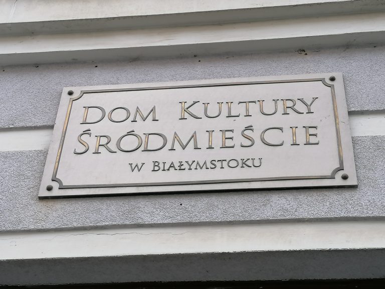 Szara tabliczka z napisem: Dom Kultury Śródmieście w Białymstoku