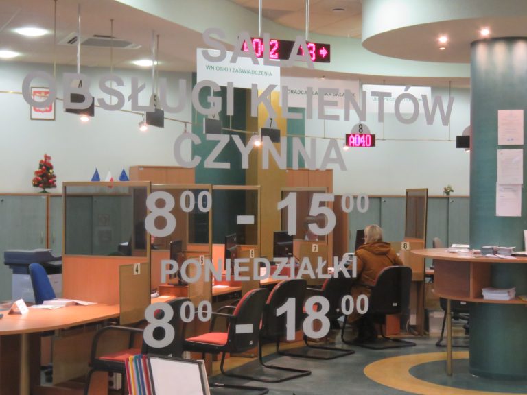 Sala obsługi klientów w ZUS. Za szybą widać biurka, na których stoją komputery.