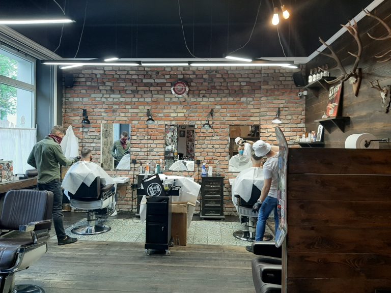 Mężczyźni siedzą na fotelach w salonie barber