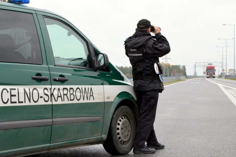 Funkcjonariusz KAS stoi przy samochodzie służbowym