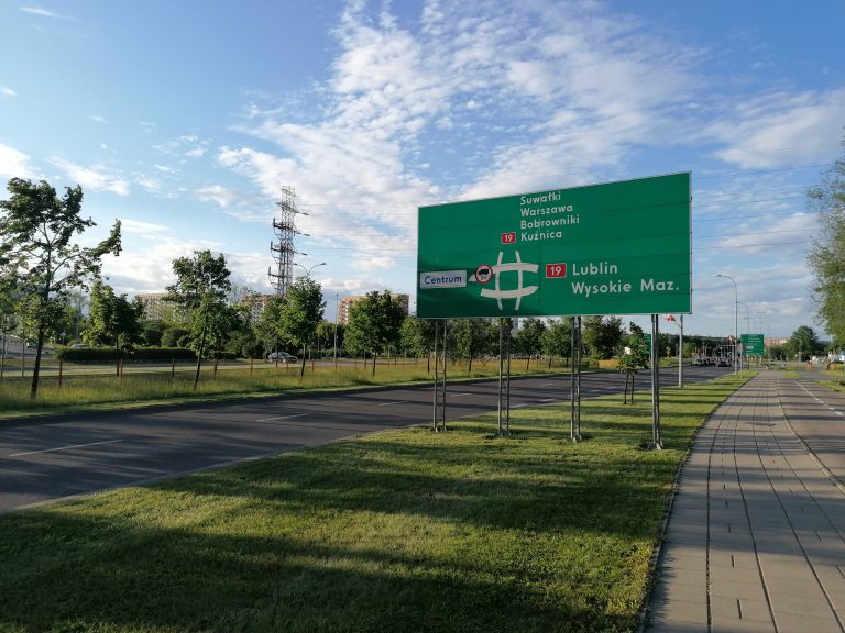 Pas zieleni a nim tablica drogowa