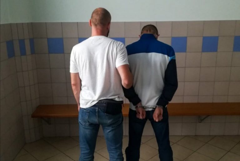 Policjant trzyma skutego kajdankami złodzieja damskiej biżuterii