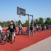 grupa młodzieży stoi z rowerami na boisku szkolnym