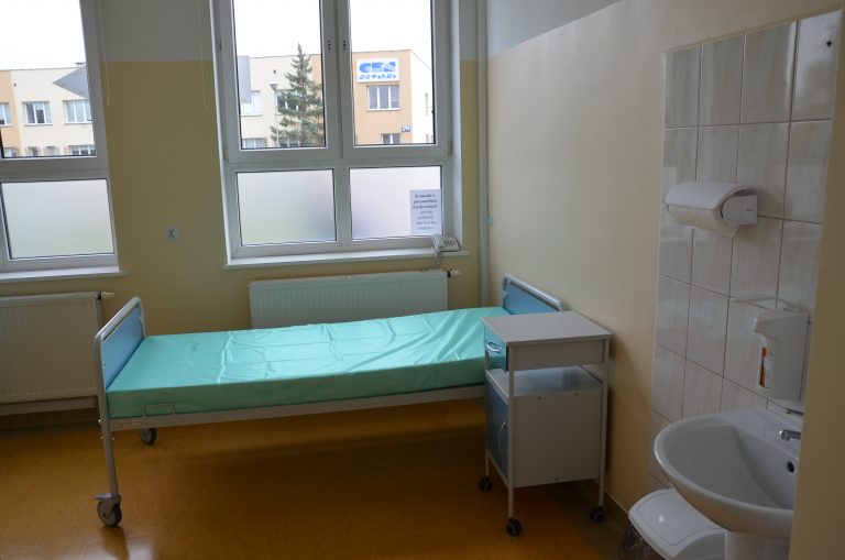 Sala szpitalna, a w niej łóżko dla chorego.