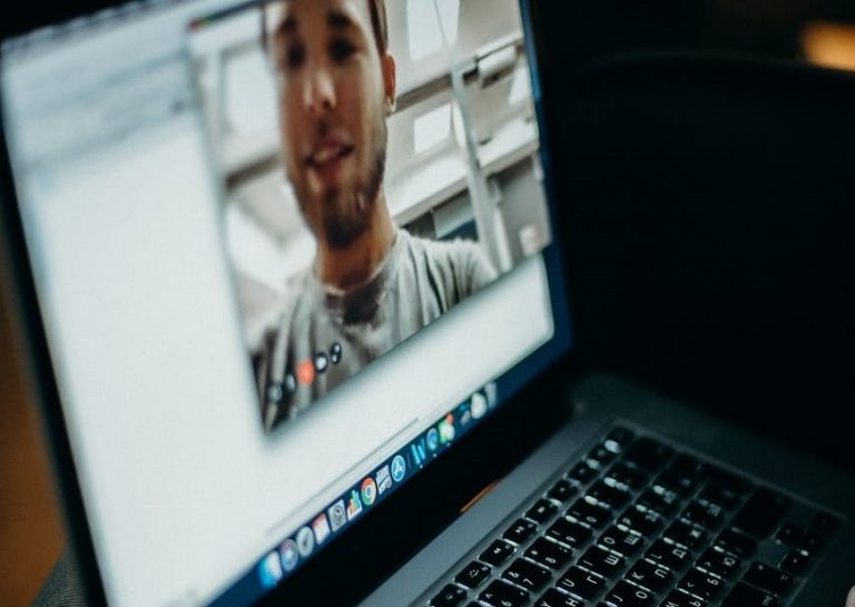 Monitor laptopa, w którym widoczny jest mężczyzna, który prowadzi videorozmowę