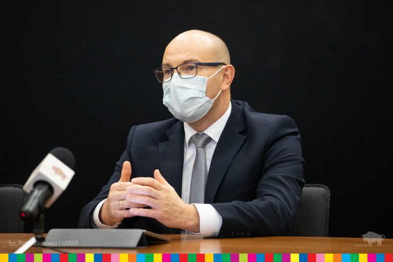 Mężczyzna w maseczce siedzi przy biurku