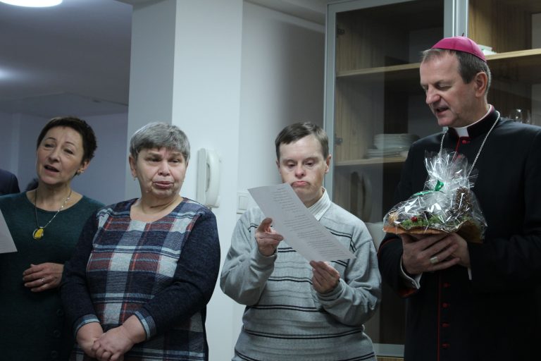 Cztery osoby stoją i śpiewają. Po prawej stronie arcybiskup Tadeusz Wojda