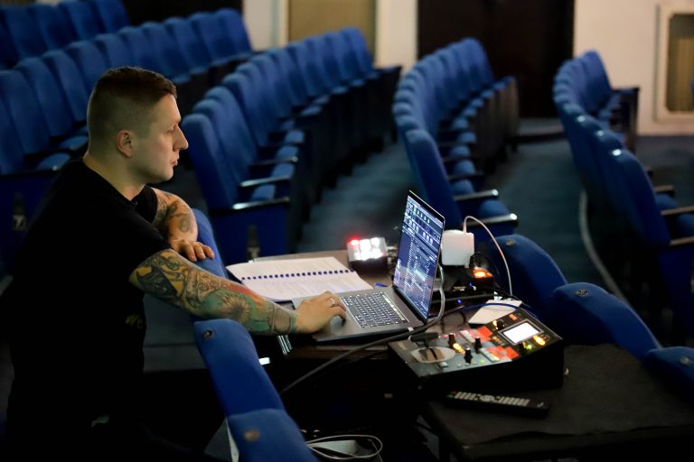 Mężczyzna siedzi przed latopem na teatralnej widowni