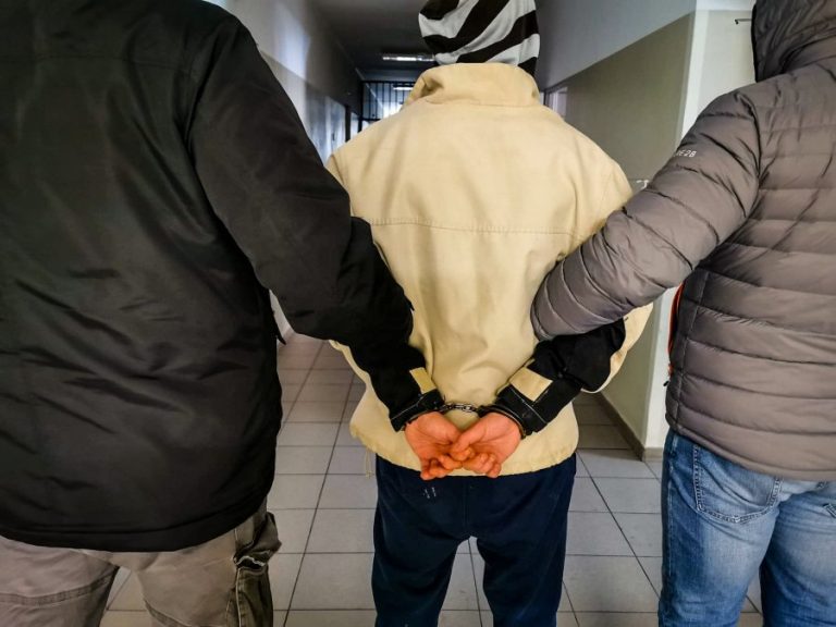 policyjni kryminalni trzymają skutego kajdankami mężczyznę