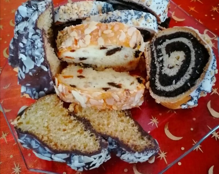 Na czerwonym obrusie leży ciasto; makowiec, keks