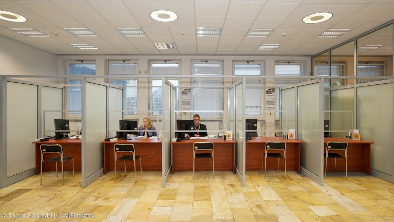 Sala Obsługi Interesantów, na którą składa się pięć stanowisk, oddzielonych od siebie szybą. Przed stanowiskami stoją krzesła, po drugiej stronie, przy komputerze siedzą urzędnicy, za nimi widoczne są duże okna