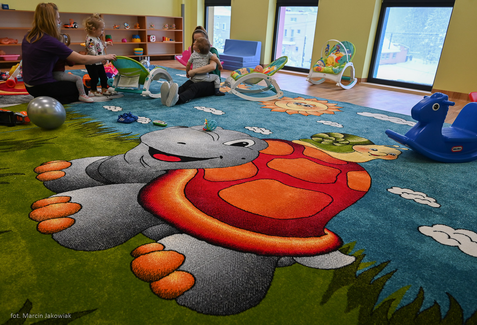 sala nowego złobka, na dywanie siedzą dzieci