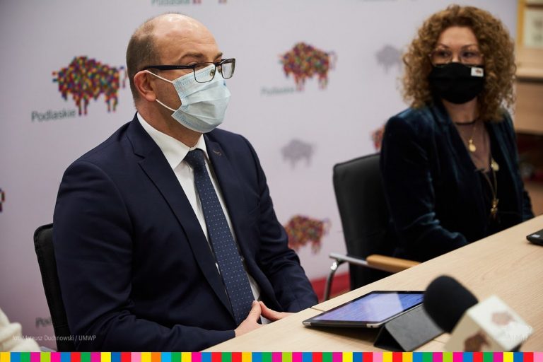 Marszałek Podlaskiego Artur Kosicki siedzi przy stole z Magdaleną Łyżnicka-Sanczenko, dyrektor Departamentu Współpracy z Zagranicą i Promocji w urzędzie marszałkowskim.
