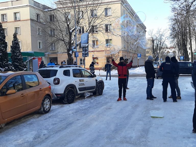 Ulica Malmeda w Białymstoku. Mężczyzna w cylindrze puszcza duże bańki, obok stoją policjanci, którzy legitymują innych uczestników manifestacji