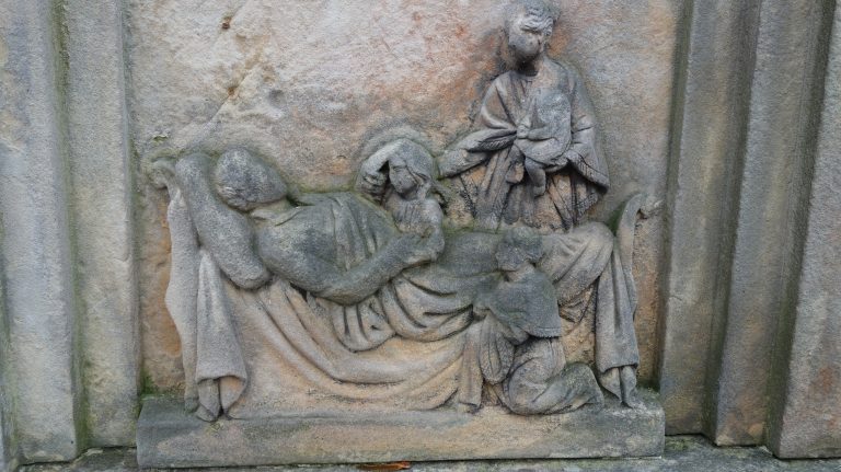 Fragment nagrobka z płaskorzeźbioną sceną ukazującą mężczyznę, zapewne na łożu śmierci, otoczonego dziećmi i kobietą trzymającą niemowlę