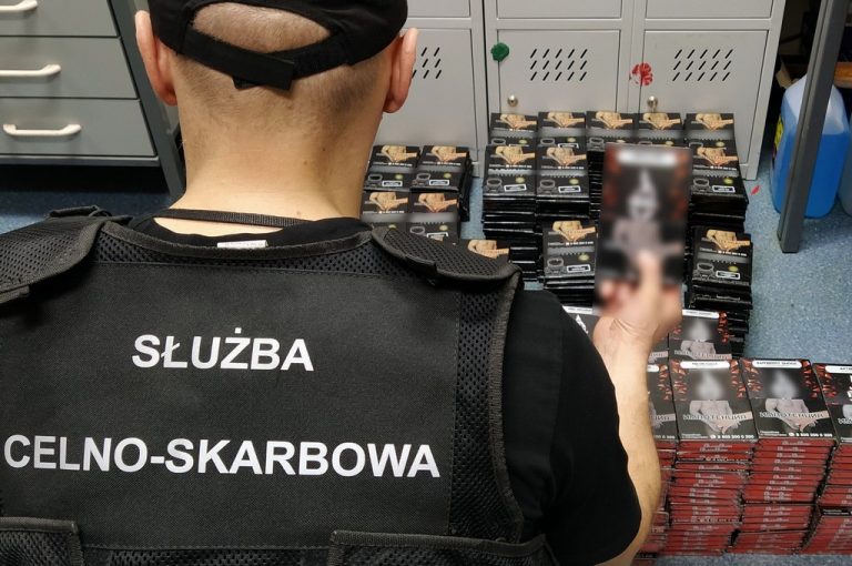 Funkcjonariusz KAS trzyma w ręku opakowanie z tytoniem do fajek wodnych