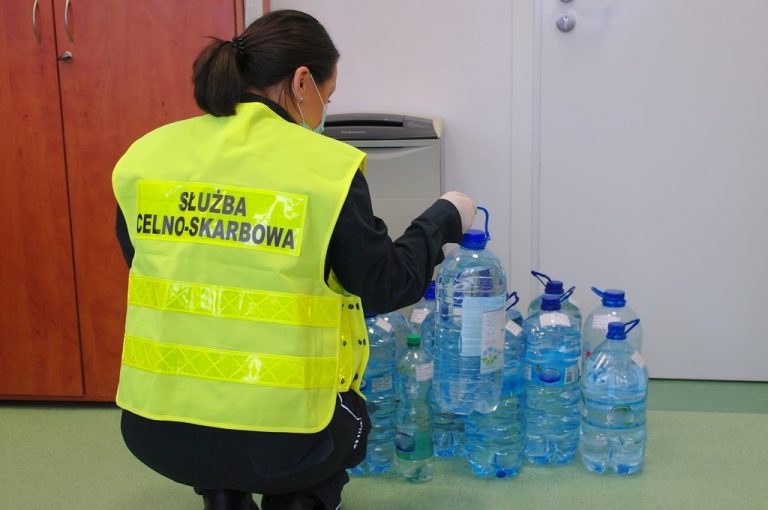 Funkcjonariuszka KAS przy plastikowych butelkach z alkoholem