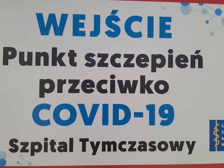 Tabliczka z napisem: Wejście. Punkt szczepień przeciwko COVID - 19. Szpital tymczasowy