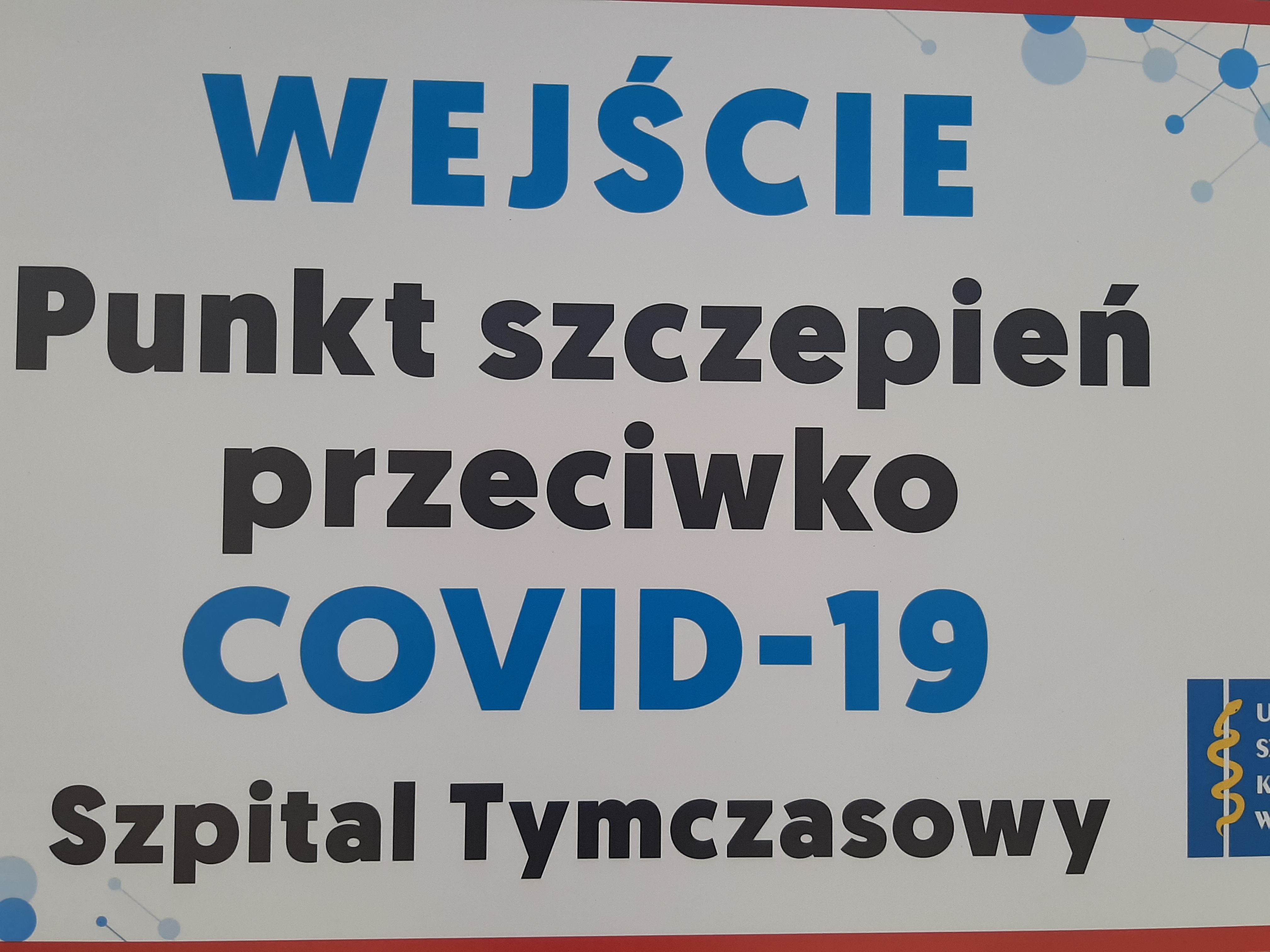 Tabliczka z napisem: Wejście. Punkt szczepień przeciwko COVID - 19. Szpital tymczasowy