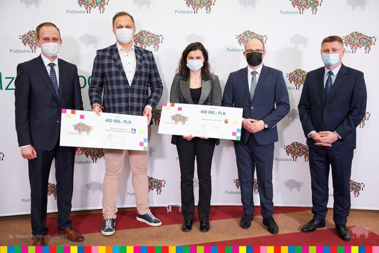 przedstawiciele klubów Jagiellonii Białystok i Ślepsk Suwałki stoją z symbolicznymi czekami