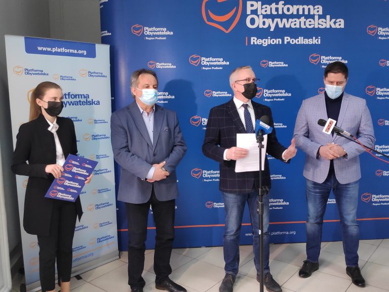 Cztery osoby stoją na tle ścianki, na której jest logo i napis Platforma Obywatelska