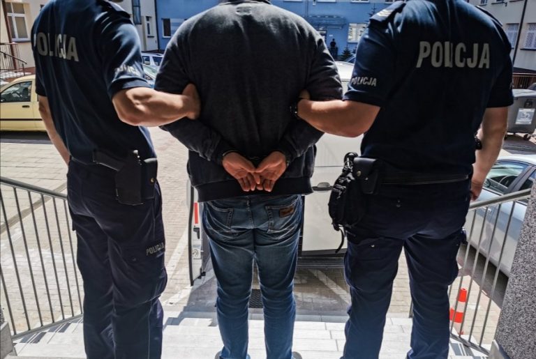 Dwaj policjanci trzymają skutego kajdankami mężczyznę