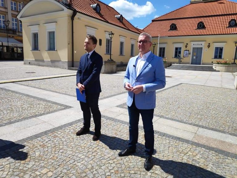 Na Rynku Kościuszki, od lewej strony stoi poseł Krzysztof Truskolaski, z prawej Robert Tyszkiewicz. Za nimi jest widoczny budynek Ratusza