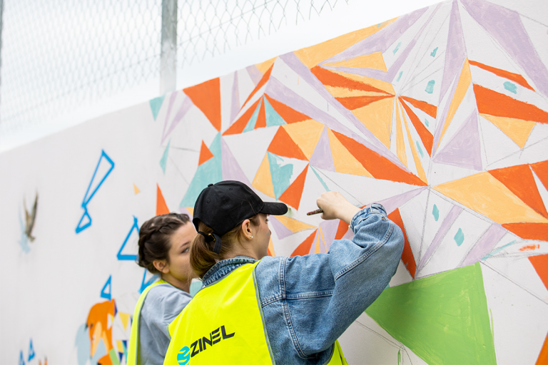 Dwie studentki malują mural na murze