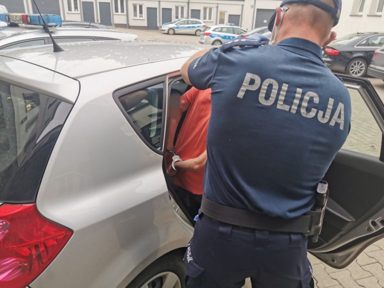 Policjant wsadza do samochodu poszukiwanego mężczyznę