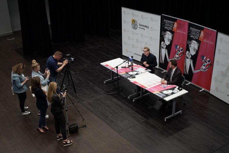 Konferencja prasowa zapowiadająca festiwal walizka. Przy stole siedzą organizatorzy imprezy, przed nimi stoją przedstawiciele mediów