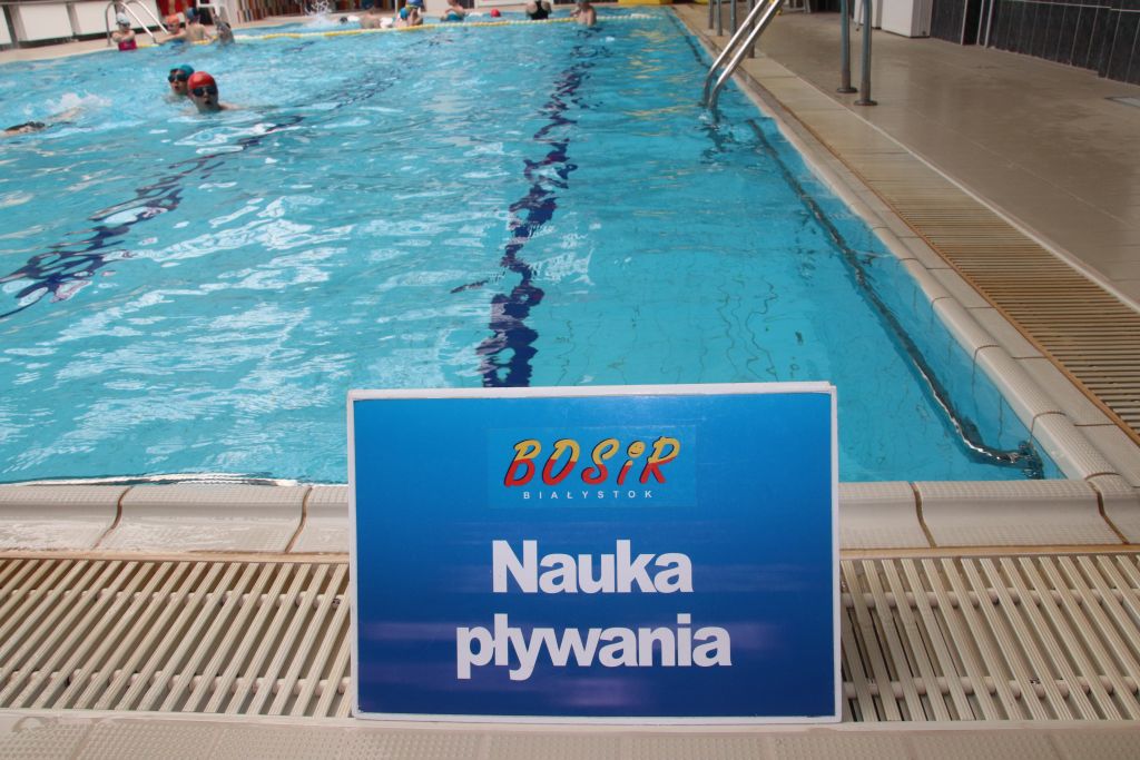 Przed basenem stoi tabliczka z napisem "nauka pływania"