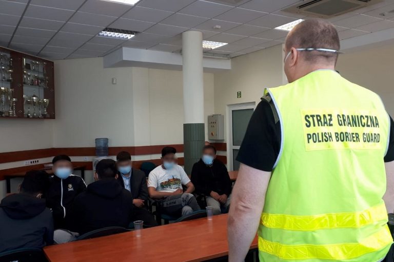 Migranci z Afganistanu siedzą w sali