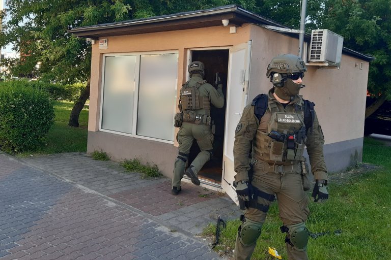 Funkcjonariusze podlaskiej KAS wchodzący do lokalu, w którym znajduję się nielegalny salon gier hazardowych, za budynkiem drzewa