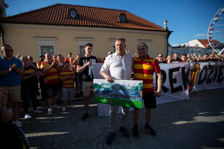Na Rynku Kościuszki stoi były prezes Jagiellonii Cezary Kulesza., z lewej strony. Obok niego znajduje się fan drużyny. Za nimi stoi grupa kibiców żółto - czerwonych, część z nich trzyma transparent z napisem: Czarek, dzięki!