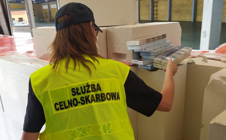 Funkcjonariuszka rozpakowuje papierosy z bloczków betonowych.