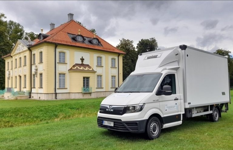 Białe auto typu dostawczak stoi przed siedzibą Muzeum Wnętrz Pałacowych w Choroszczy