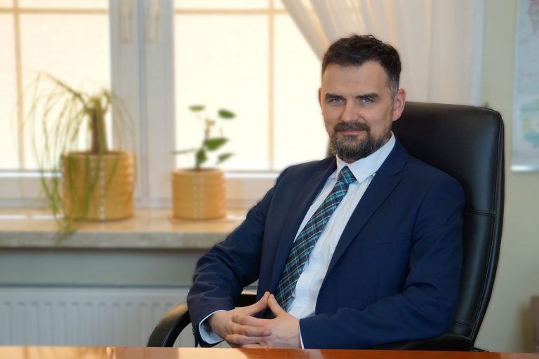 Mężczyzna siedzi w fotelu, przy biurku