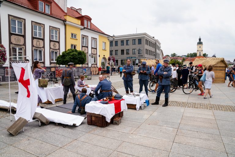 Na Rynku Kościuszki w Białymstoku siedzą i stoją rekonstruktorzy ubrani w szaroniebieskie mundury