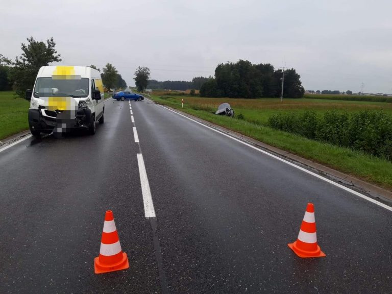 Na drodze ustawione są pachołki, w tle rozbity bus, opel w rowie i policyjny radiowóz