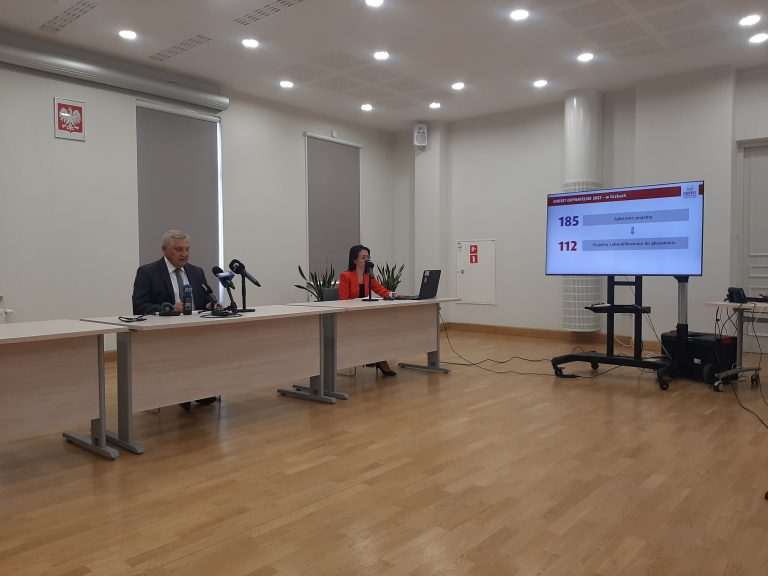 Sala Centrum Aktywności Społecznej. W oddali siedzi mężczyzna i kobieta, po prawej stronie soi telewizor