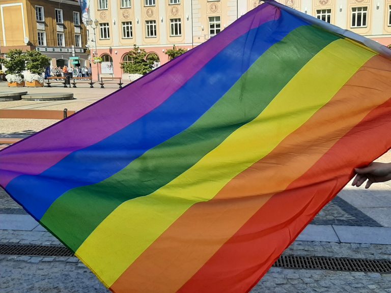 Flaga w różnokolorowe pasy; od góry fioletowo - granatowo - zielono - żółto -pomarańczowo - czerwone