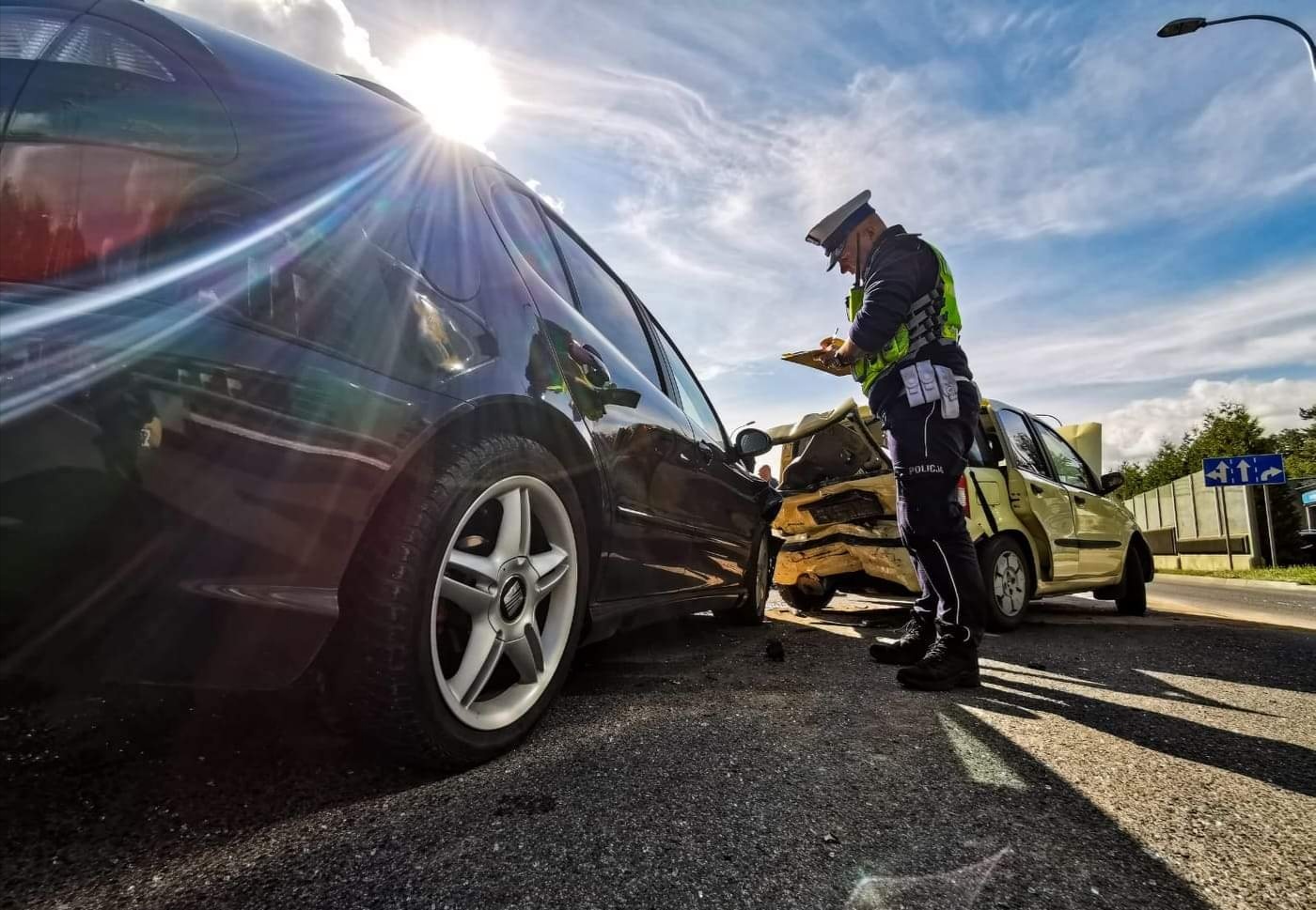 Policjant sporządza służbową notatkę w miejsu wypadku