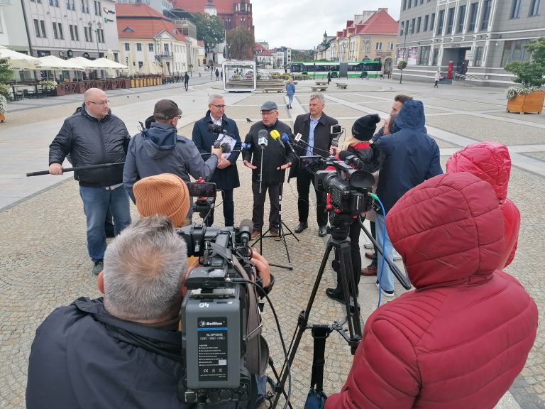 Konferencja prasowa na Rynku Kościuszki. Stoi grupa dziennikarzy trzymających mikrofony. Przemawiają przedsiębiorcy i polityk