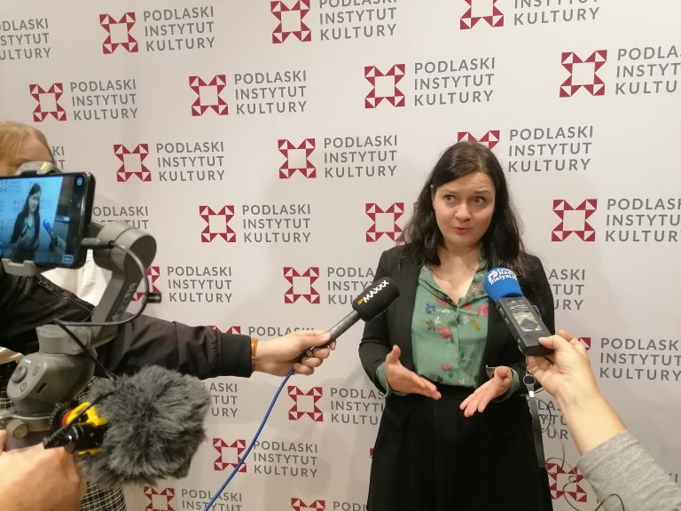 Kobieta mówi do mikrofonów na tle ścianki PIK