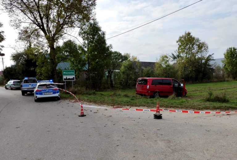 Bus stoi na trawie, obok stoją policyjne radiowozy