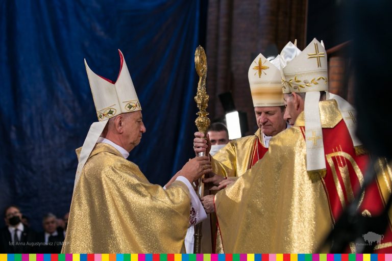 Księża w złotych szatach przekazują sobie pastorał