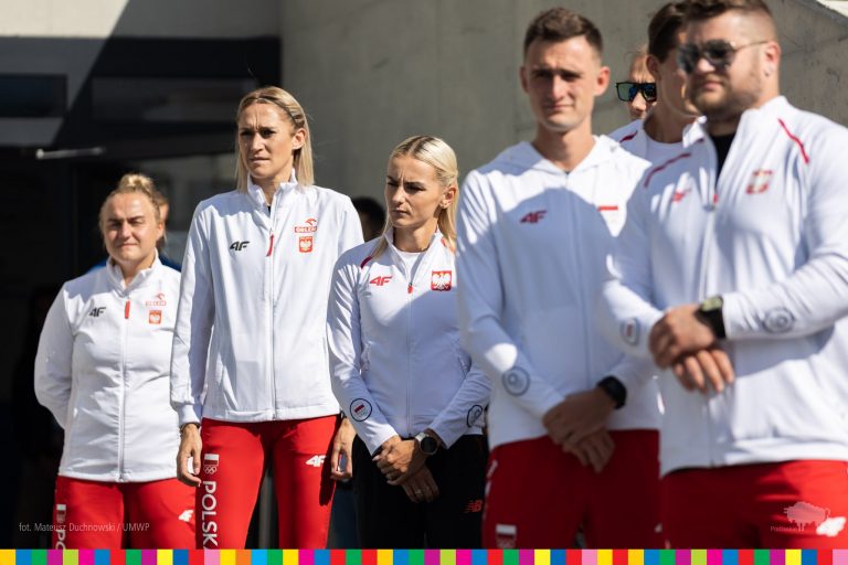 Sportowcy w biało - czerwonych dresach stoją obok siebie